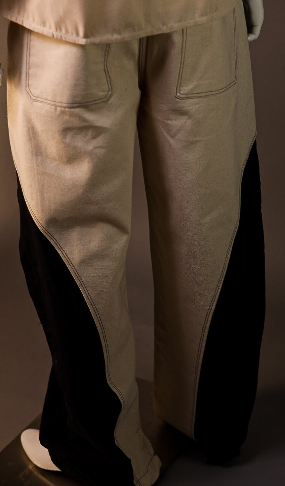 Beige pants with black accents on a plain background