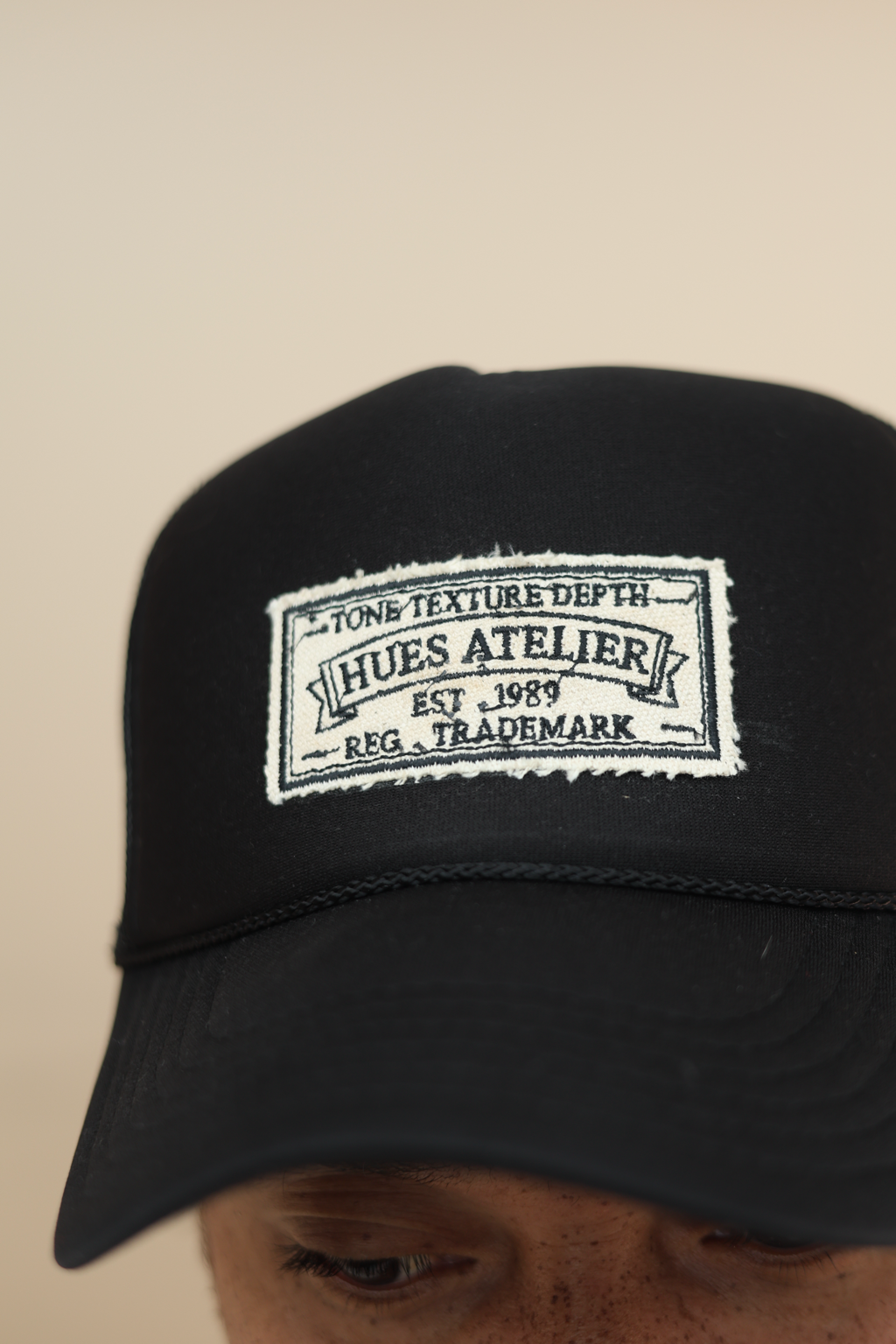 Black Hues Atelier Trucker Hat with mesh back and logo patch