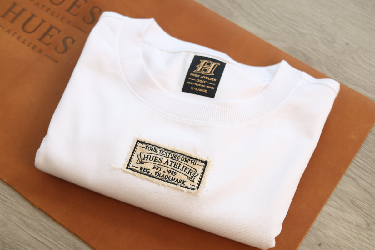 Folded ivory Hues Atelier T-shirt displaying signature brand labels