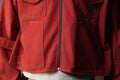 Close-up of a red jacket with a zipper and pockets.