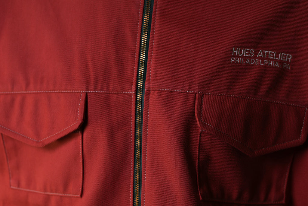 Red jacket with a zipper and 'Hues Atelier Philadelphia PA' branding.