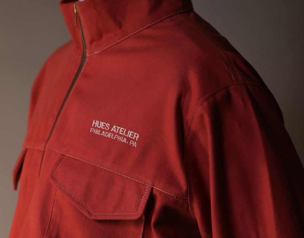 Red jacket with 'Hues Atelier Philadelphia, PA' logo on a gray background